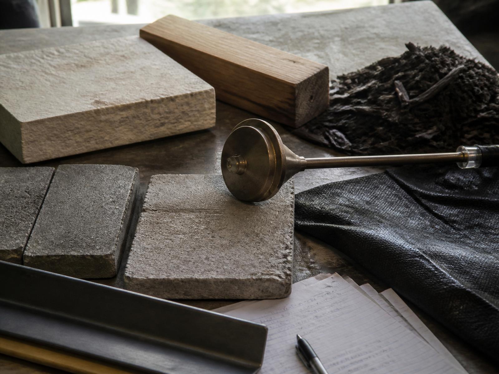 Flat lay of premium landscaping materials: paver, Indiana limestone, cedar block, brass low-voltage light and black mulch